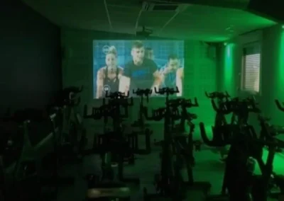 Salle de cours collectifs virtuels Fitaccess avec séance fitness diffusée sur écran géant