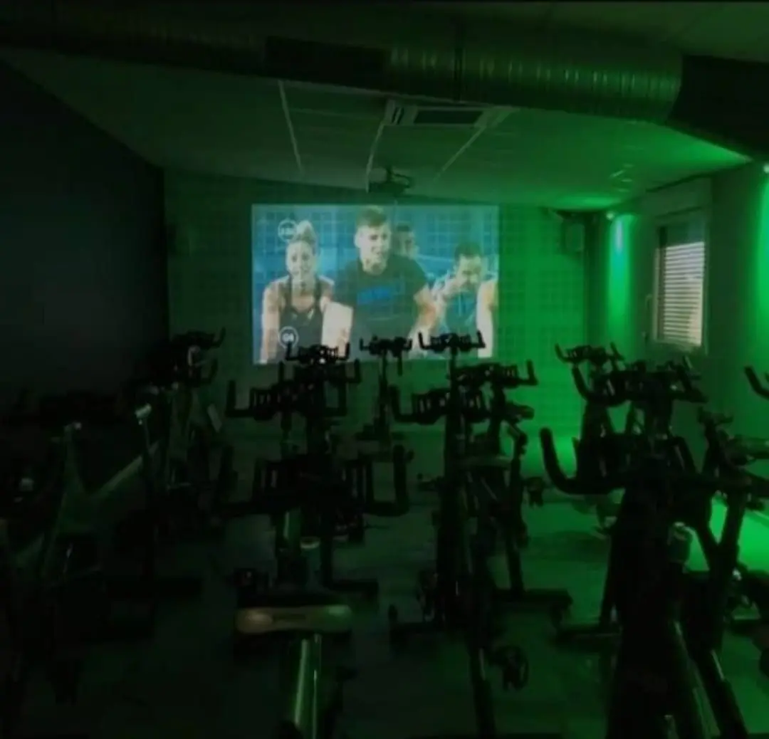 Salle de cours collectifs virtuels Fitaccess avec séance fitness diffusée sur écran géant