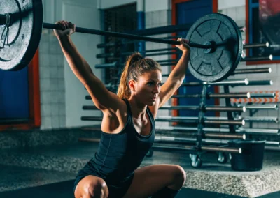 Sportive réalisant un mouvement d'haltérophilie lors d'une séance de Cross Training