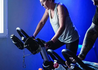 Adhérente participant à une séance RPM de vélo indoor encadrée par un coach Fitaccess